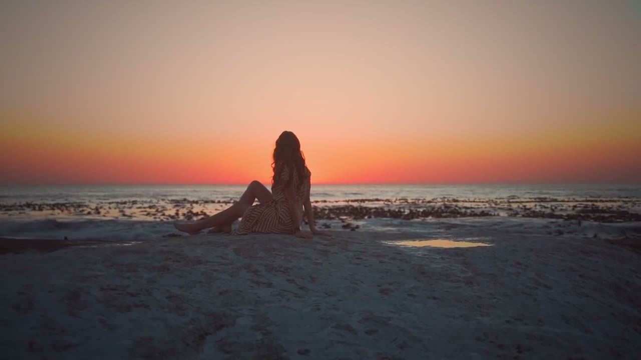 Una mujer contempla el mar al atardecer